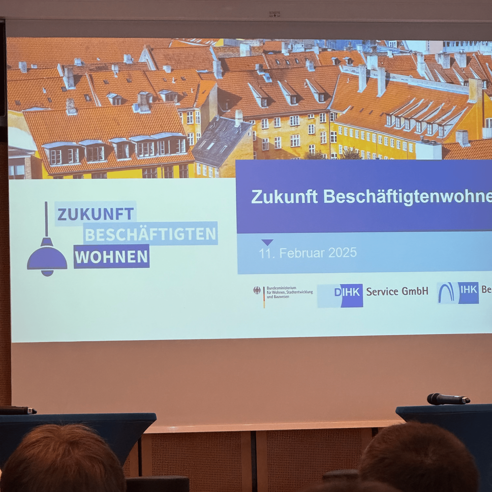 Auf einer Leinwand ist die Titelfolie der Veranstaltung zu sehen