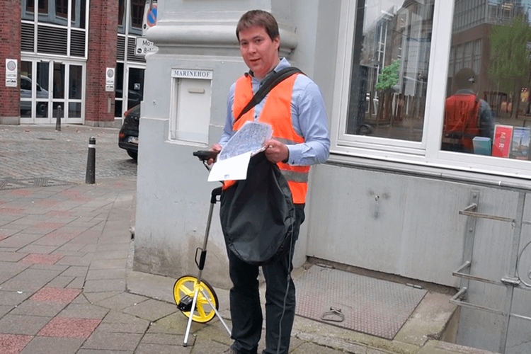 Stefan Brauckmann bei Geländebegehung mit GPS-Gerät, Messrad, Fotoaparat und diversen Karten